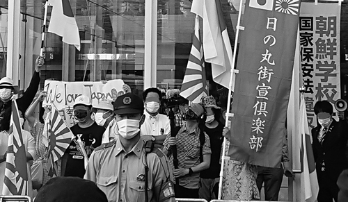 市職員が立ち会う中で行われたヘイト宣伝。手前は機動隊員。「朝鮮学校は国家保安法違反」のノボリ旗も見える（7月12日、編集部撮影）。